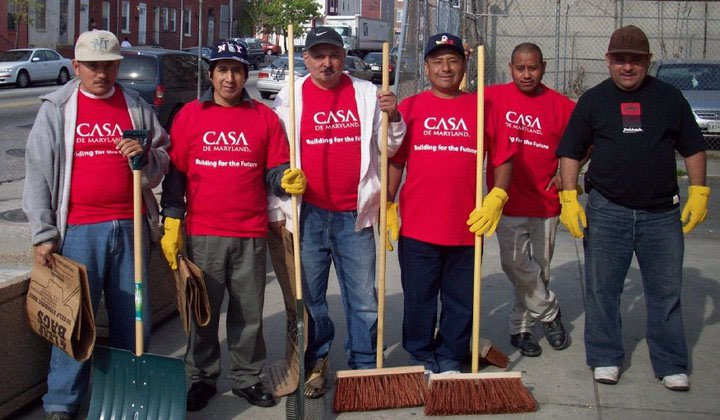 6 CASA workers in CASA t-shirts with brooms and shovel