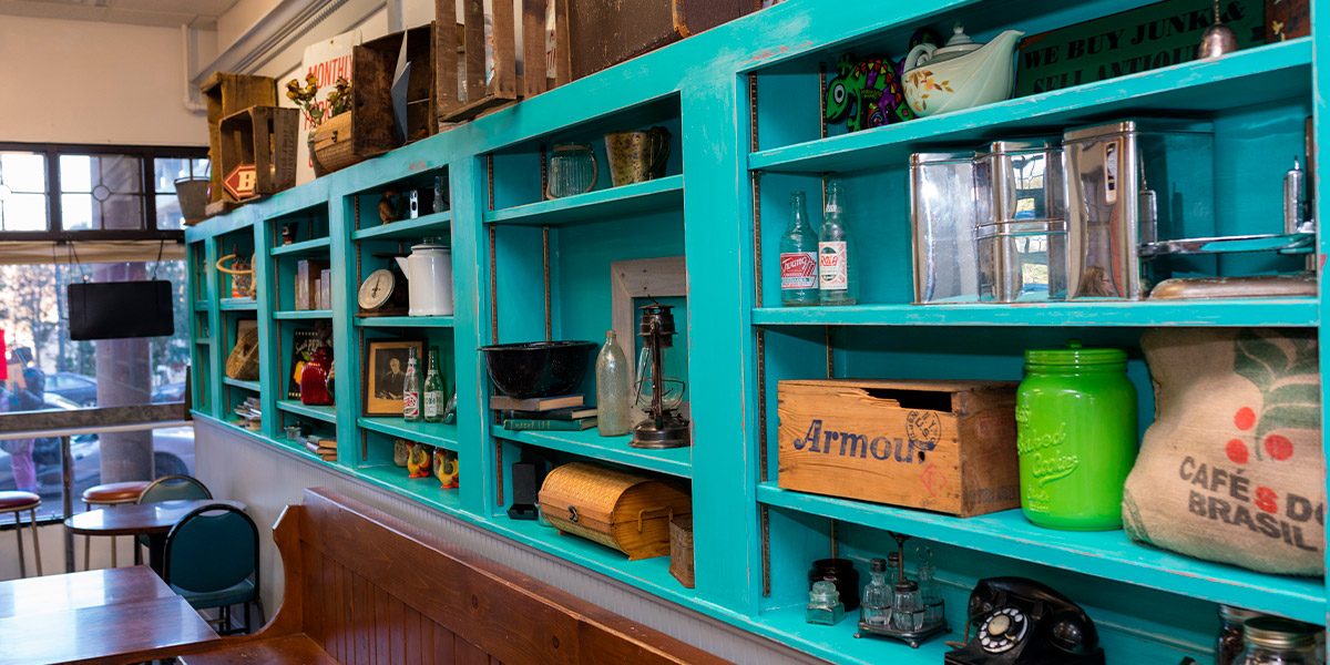 An image of a bright blue shelf with various nick-nacks inside Chameleon Cafe in downtown Akron.
