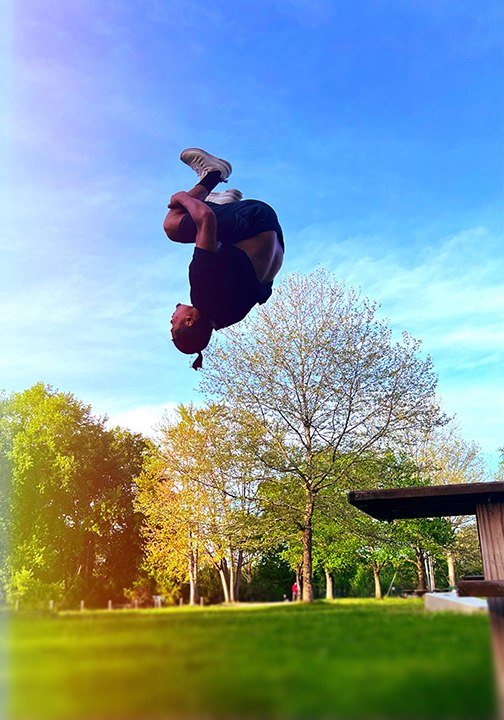 Photograph of Dinesh Sunar doing an impressive backflip in a park.