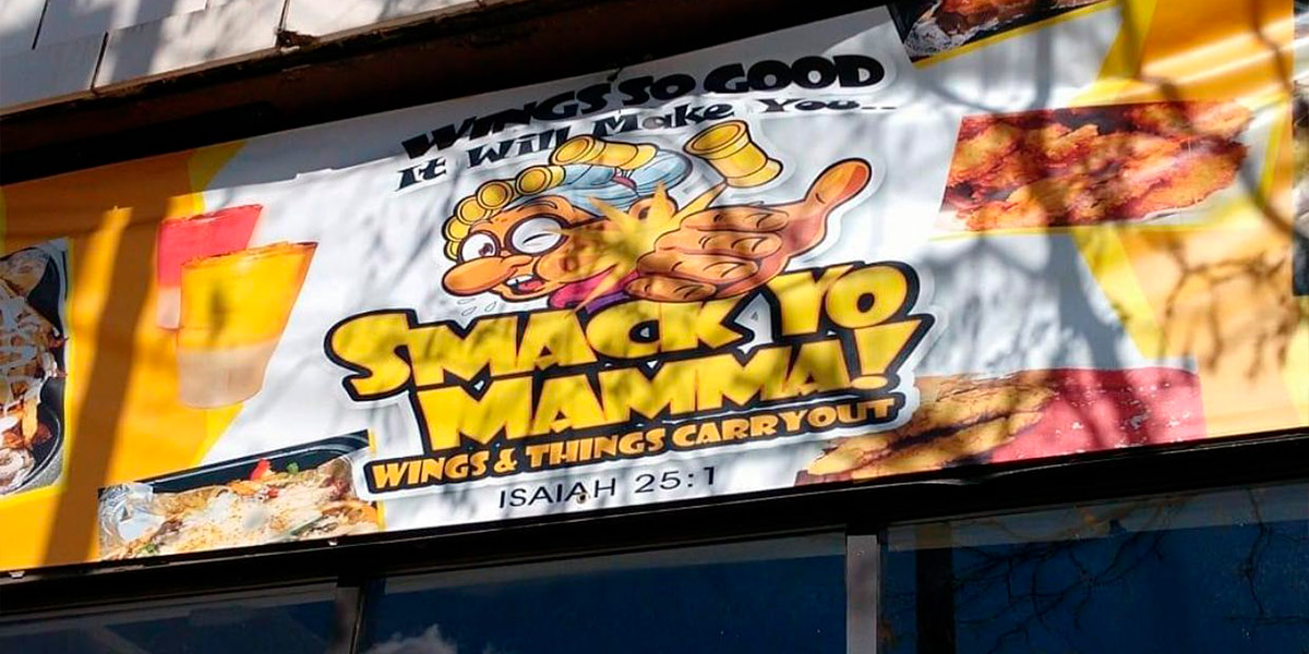 An image of the sign outside of Smack Yo Mamma Wing's & Things which features a cartoon image of a grandma.